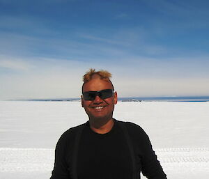 Cliff Simpson-Davis poses smiling on ice in Antarctica