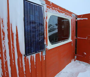 Solar panels for charging hut radio bateries stuck to the side of the building.