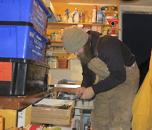 Jeremy Little at Colbeck HUt looking through boxes in a small hut.