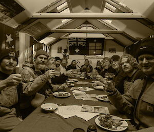 Expeditioners raising a midwinter toast. The photo is sepia coloured to look like old-fashion