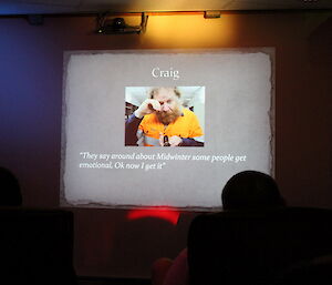 Projector screen with a photo of Craig rubbing his eyes as if he is crying.