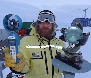 Craig Hayhow stading outside holding two different instruments.