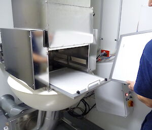 A person lifts a white tray out of the sample box.