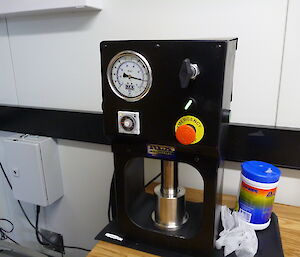 Black box with gauge and red emergency button.