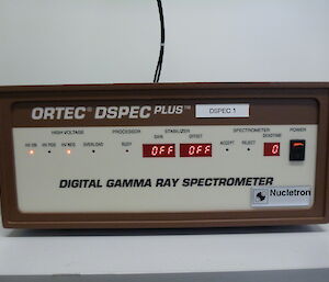 Gamma Ray spectrometer is a brown box with digital numbers and lights.