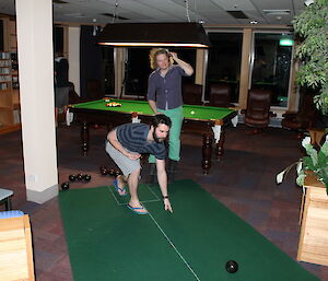 Indoor bowling pitch rolled out with expeditioner rolling the bowl.