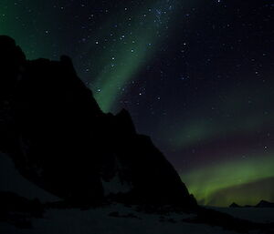 Aurora near Rumdoodle with green lights behind a dark hill.