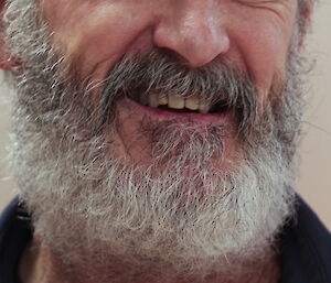Photo of a man’s face from the nose down with a grey beard.