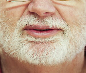 Photo of a man’s face from the nose down with a white trimmed beard.