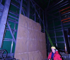 Man standing wearing hard hat at the base of the plywood climbing wall