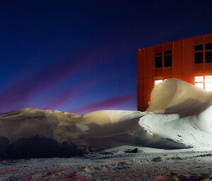 Mawson Red Shed a night with the lower windows lit up.