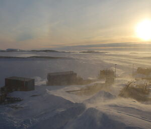The view of the Mawson buildings from the Dog Room with a pale sun on the horizon