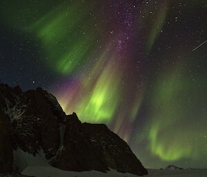 Purple and green shafts of light against the night sky.