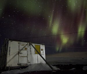 Square silver shed surrounded by green aurora lights.