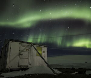 Square silver shed surrounded by green aurora lights.