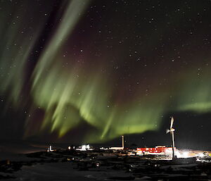 The ligths are blazing on the stations and the aurora in the sky behind.