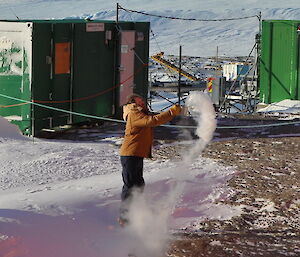 Person throwing water in the air from a pot.