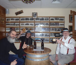 Three men dressed in leather shorts raising their glasses