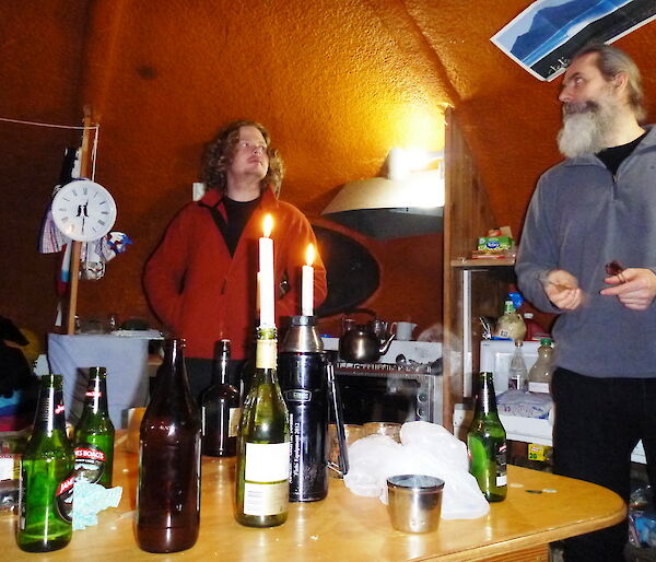 Two people standing inside the hut holding darts