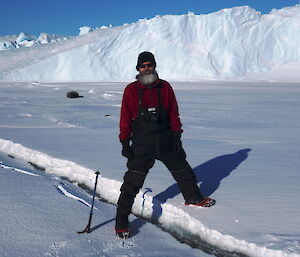 Man stands with one leg on either side of a tide crack