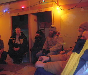 People sitting around in an old hut.