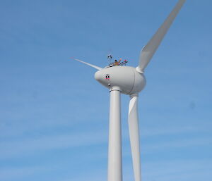 Person looks tiny as they wave from the top from wind turbine