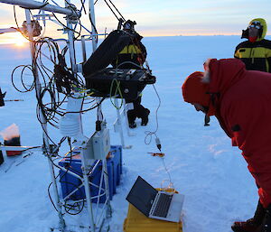 Man peering at the Automatic weather station to check it is working.