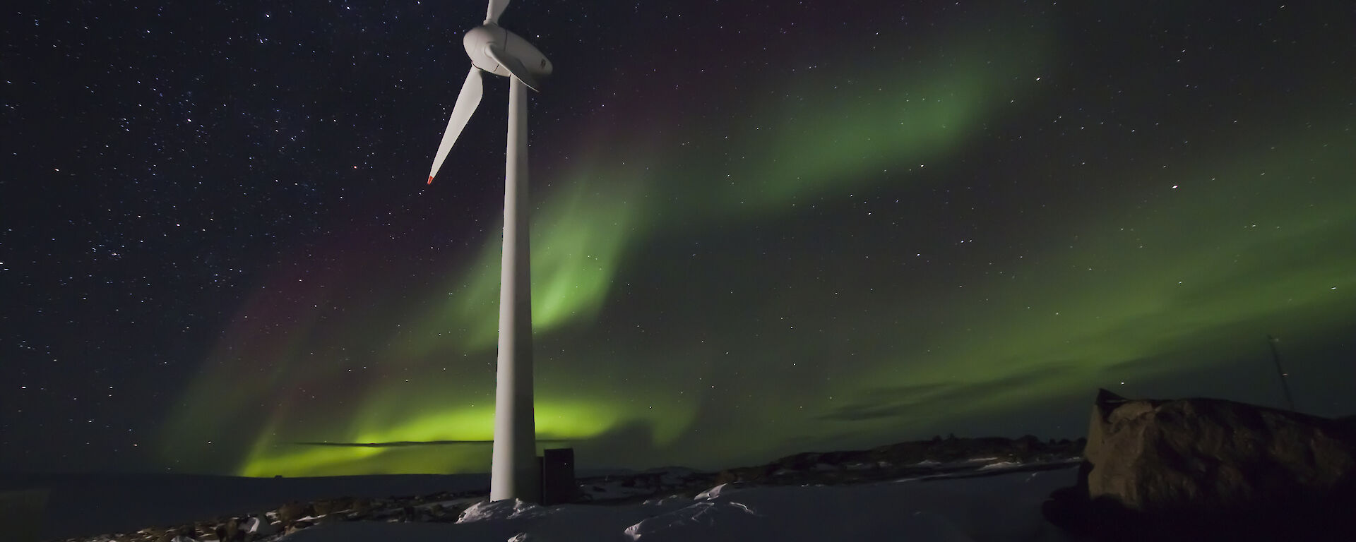 Mawson wind turbine with green aurora in the sky