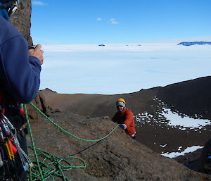 One man holds the rope secure while the other lowers himself over the edge of the Fang Peak.