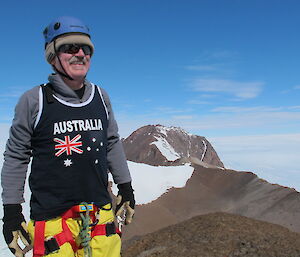 The author smiling on the summit with Fang Peak Mt Elliott behind.