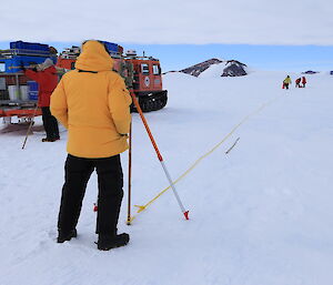 Surveyer measuring with distances roped out across the ice.