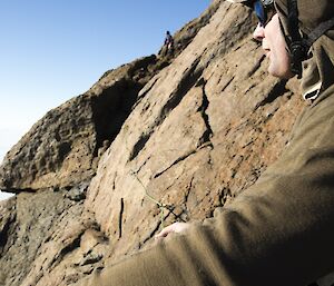 Expeditioner wearing climbing helmet belaying on Rumdoodle