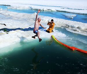 Man wearing boardshorts jumping into ice water