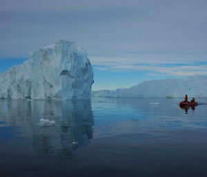 Expeditioners in a small inflatable boat surrounded by medium-sized icebergs