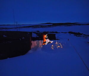 Expeditioner standing beside his bivvy camp protected by snow blocks