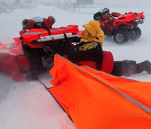 Setting up a quad survival bivvy tent between two quad bikes in a blizzard