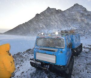The blue Hägg parked out the front of Hendo hut with blowing snow in the air