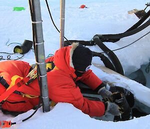 A tradesman lying on the deck of the melt bell as he hands equipment to a mate working inside the melt bell