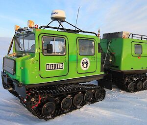 A green Hägglunds outside in snow at Mawson Station
