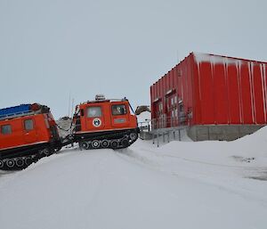 A Hägglunds driving around Mawson station, the red shed to the right