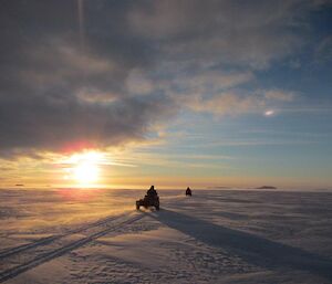 expeditioners riding across the sea ice on their quad motorbikes