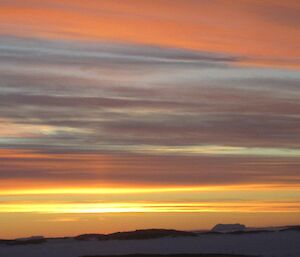 View of the sun setting across Horseshoe Harbour streaking the sky with brilliant, loud colour