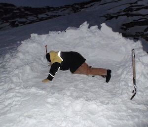 An expeditioner cleaning up and padding down the snow so as to sleep on it