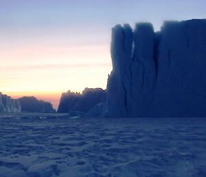A setting sun over icebergs creates a dreamy, surreal moonscape