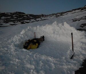 An expeditioner lying on his back in the padded out snow bed