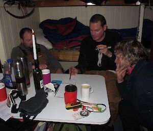 Three expeditioners inside Rumdoodle hut planning a search and rescue response