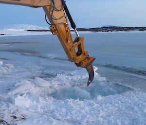 The excavator breaking a hole through the sea ice for the swimming hole