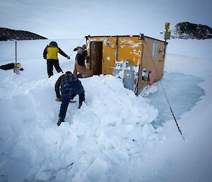 The team digging out the hut with shovels and a generator-powered jackhammer