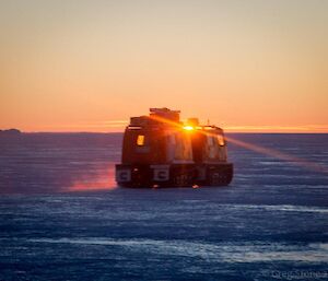 Hägglunds driving off across the sea ice and into the sunset