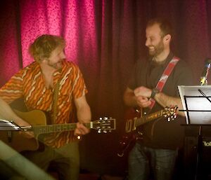 The acoustic guitarist and electric guitarist having a laugh together